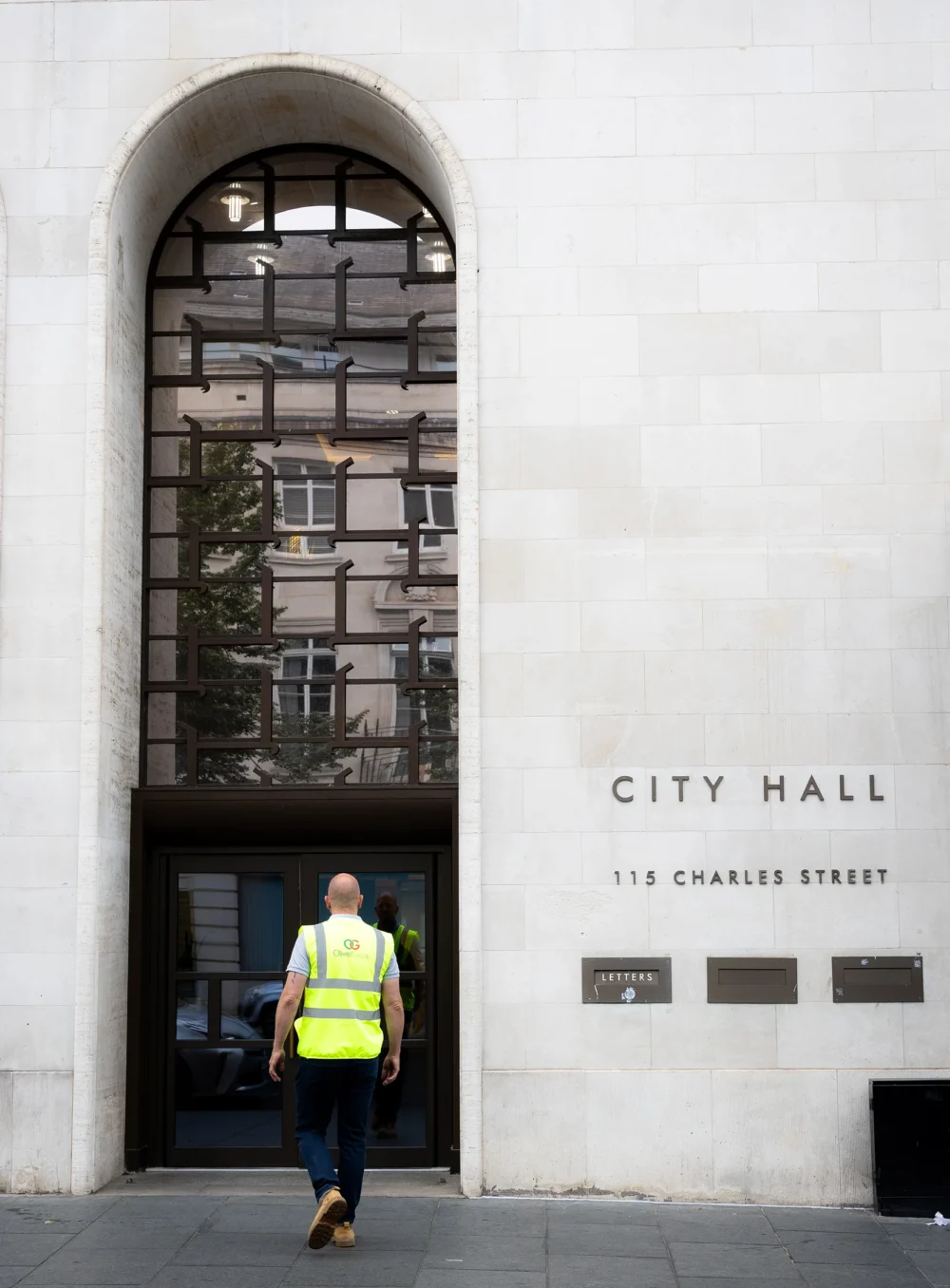 A man in high vis entering a city hall.