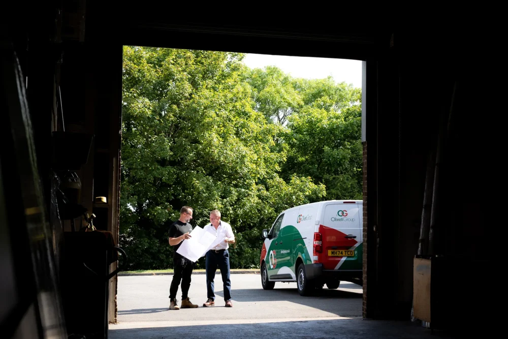 Oliveti van and 2 people looking at plans