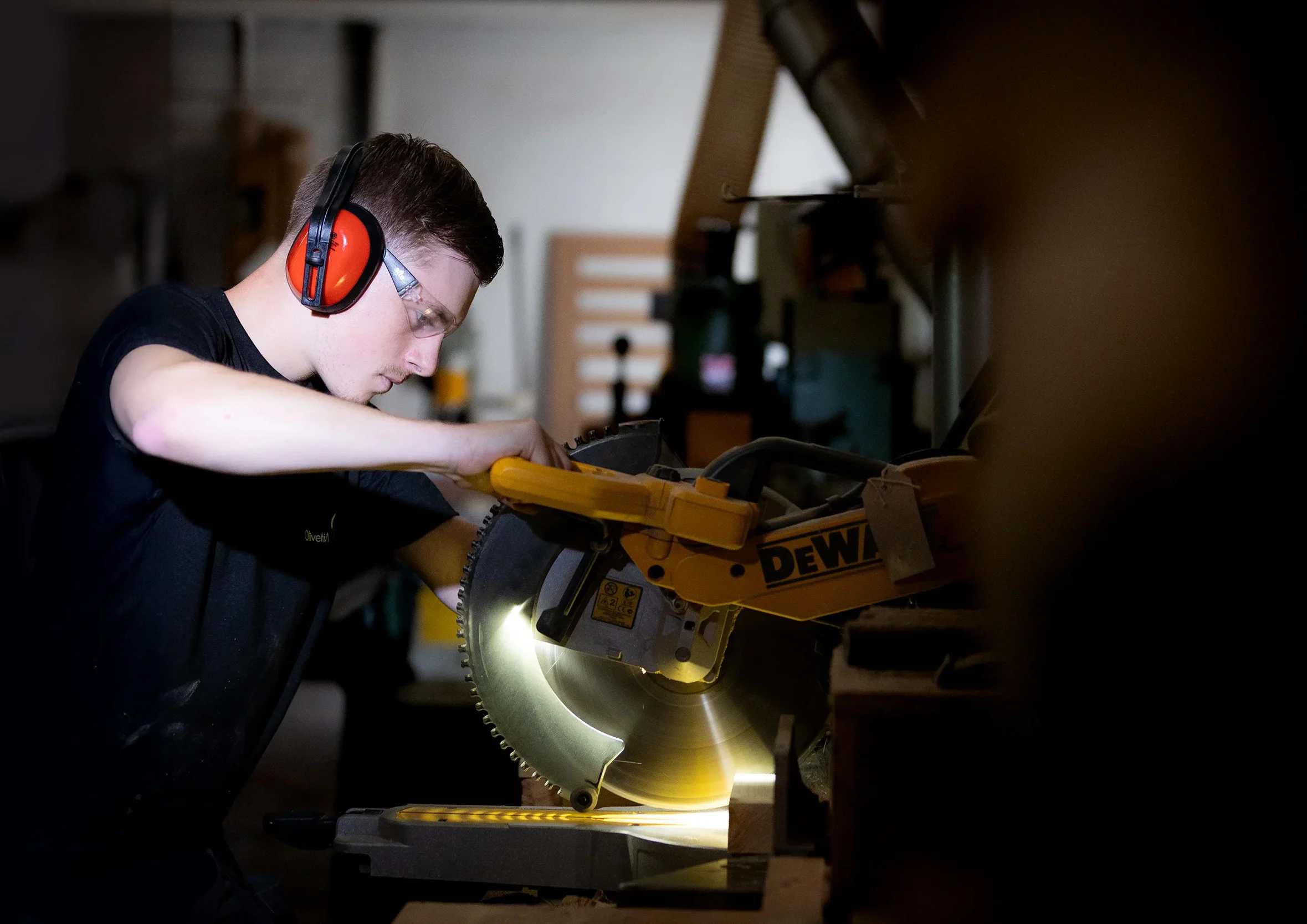 A workman wearing ear defenders and using a circular saw.
